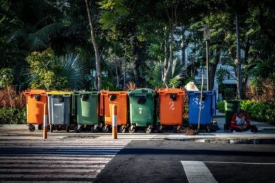 Line of Seven Trash Cans in Orange, Green, Blue and Grey