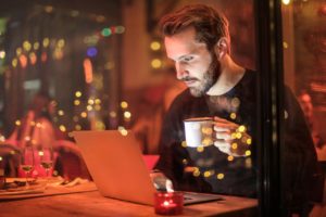 Man working on his laptop in a night setting with reflecting lights.