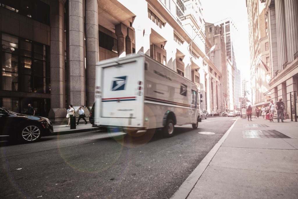 Mail Truck Driving Down a City Road